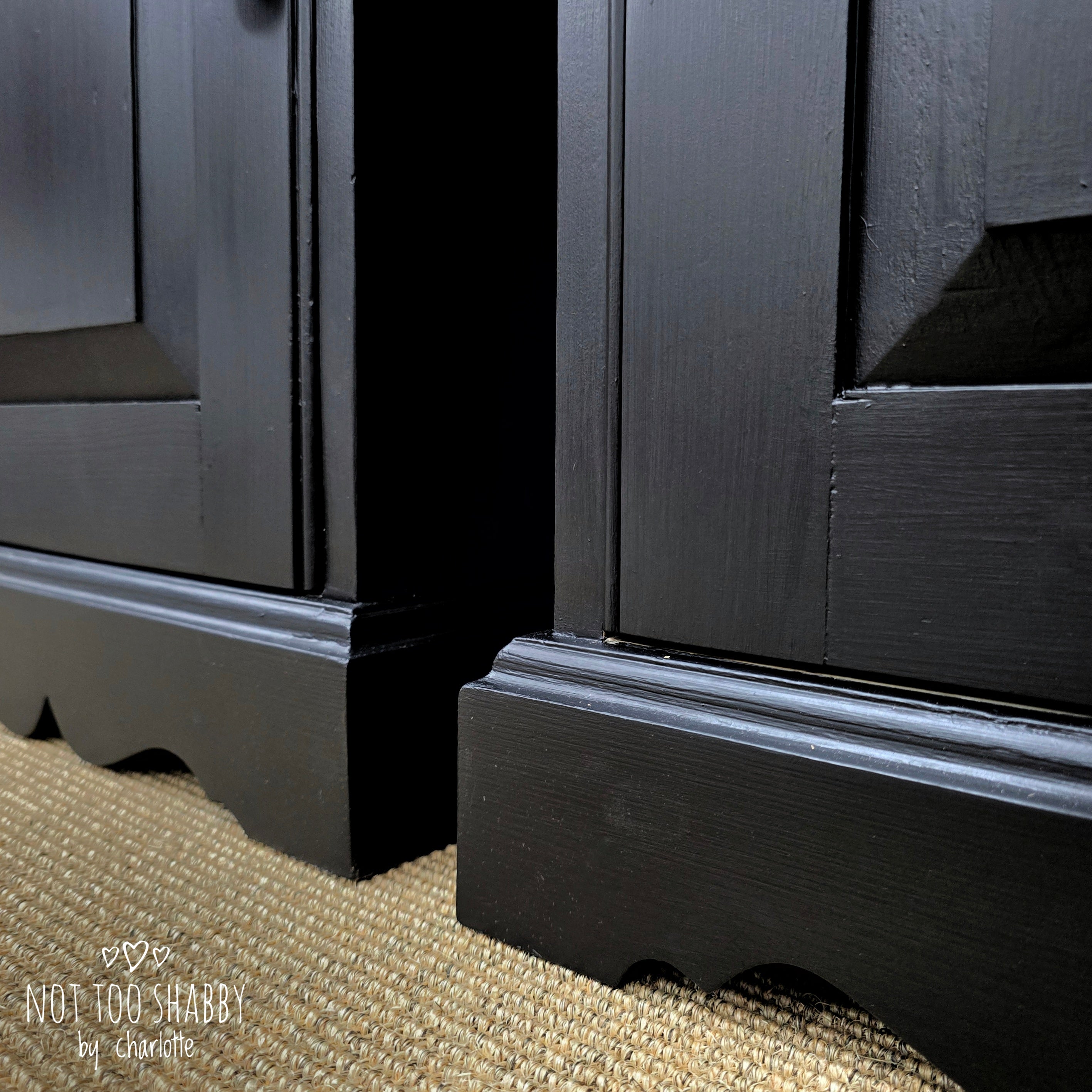 Close up of the base trim of a pair of Coal Black painted pine cupboards with silver knobs and hinges