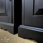 Load image into Gallery viewer, Close up of the base trim of a pair of Coal Black painted pine cupboards with silver knobs and hinges
