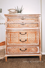 Load image into Gallery viewer, Elegant Vine Redesign with Prima Stencil repeated in white over orange teak wood
