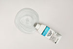 Load image into Gallery viewer, Bottle of Silver Polyvine Metallic Paint being poured onto a pale grey surface
