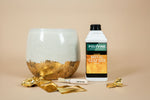 Load image into Gallery viewer, Polyvine acrylic metal leaf size bottle with gold leaf and a decorative bowl on a beige background
