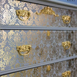Load image into Gallery viewer, Renata Floral Damask Redesign with Prima Stencil feom the Kacha Collection in gold leaf on a blue grey chest of drawers
