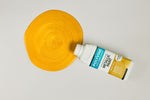 Load image into Gallery viewer, Bottle of Bright Gold Polyvine Metallic Paint being poured onto a pale grey surface
