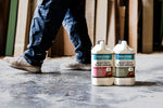 Load image into Gallery viewer, Two 4 litre bottles of Polivine heavy-duty floor varnish on a concrete floor with a person walking working in the background.
