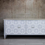 Load image into Gallery viewer, Anisa Redesign with Prima Damask Stencil from the Kacha Collection stencilled in white on a grey sideboard
