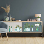 Load image into Gallery viewer, Vintage Greenhouse Redesign with Prima Middy Transfer - watercolour vases and bottles with a mixture of leaves and foliage displayed in them across the front of a sideboard with sliding doors
