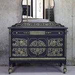 Load image into Gallery viewer, Anisa Redesign with Prima Damask Stencil from the Kacha Collection stencilled in gold on an ornate black vintage sideboard

